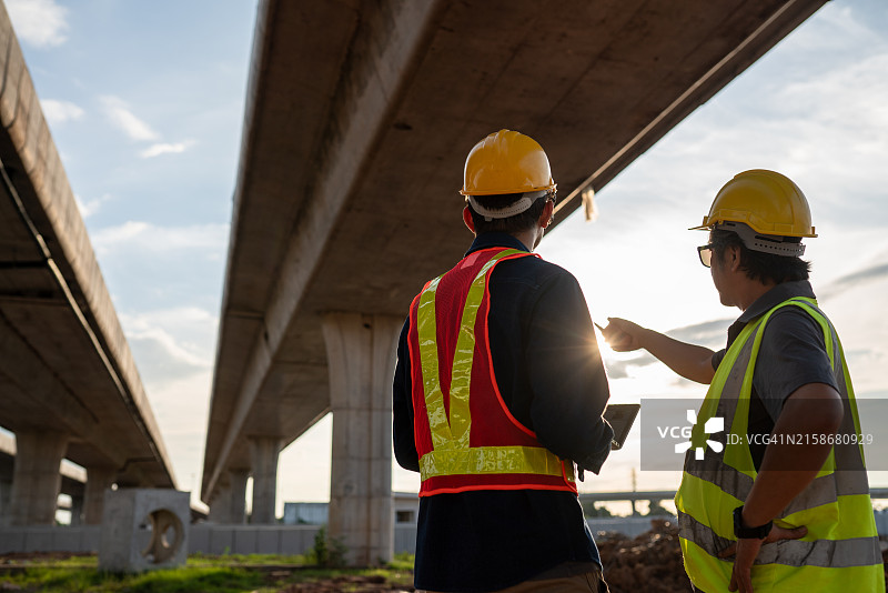 身穿施工背心的工程师和工头指向一座桥图片素材