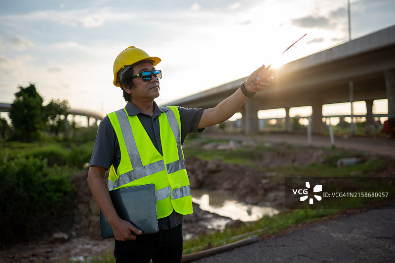 一名穿黄色背心的男子指向一座桥图片素材