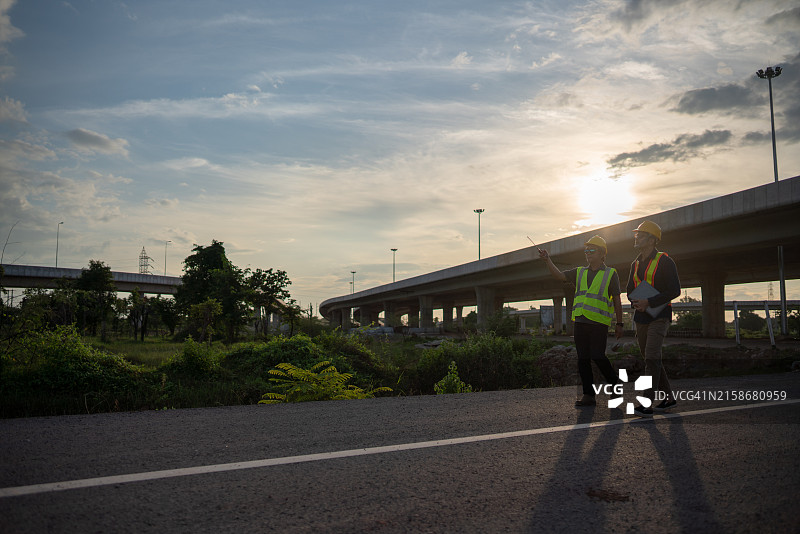 站在路上，一人指向天空的两名建筑工人图片素材
