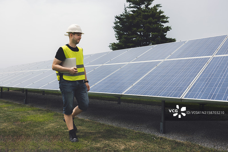 工人在太阳能电池板附近使用笔记本电脑图片素材