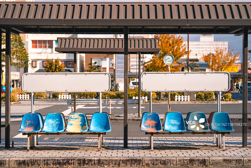 阳光明媚的公交车站旁废弃的蓝色座椅图片素材