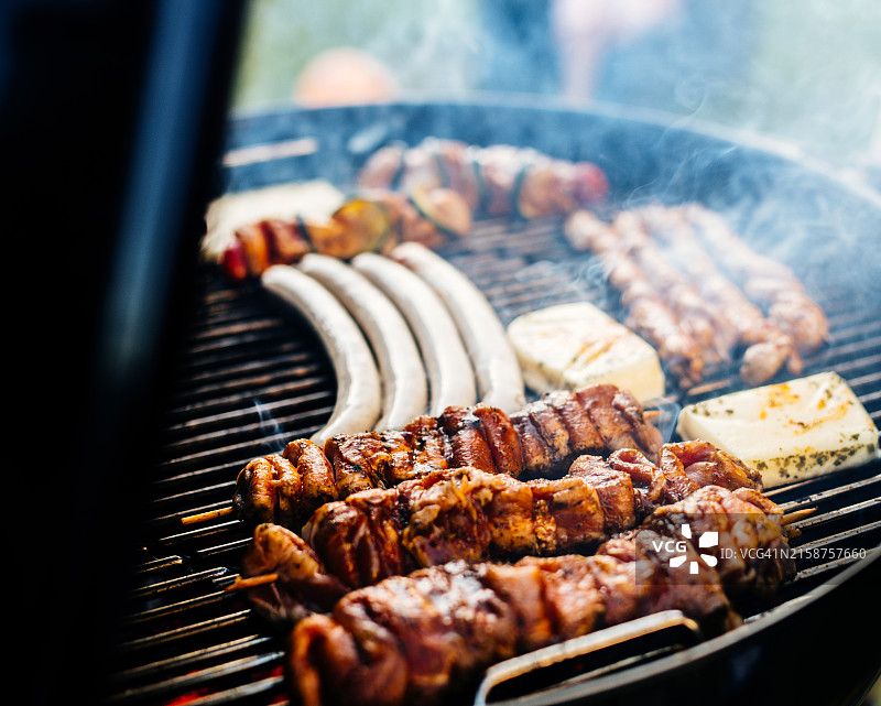 男人在烤架上烧烤牛排和香肠。图片素材