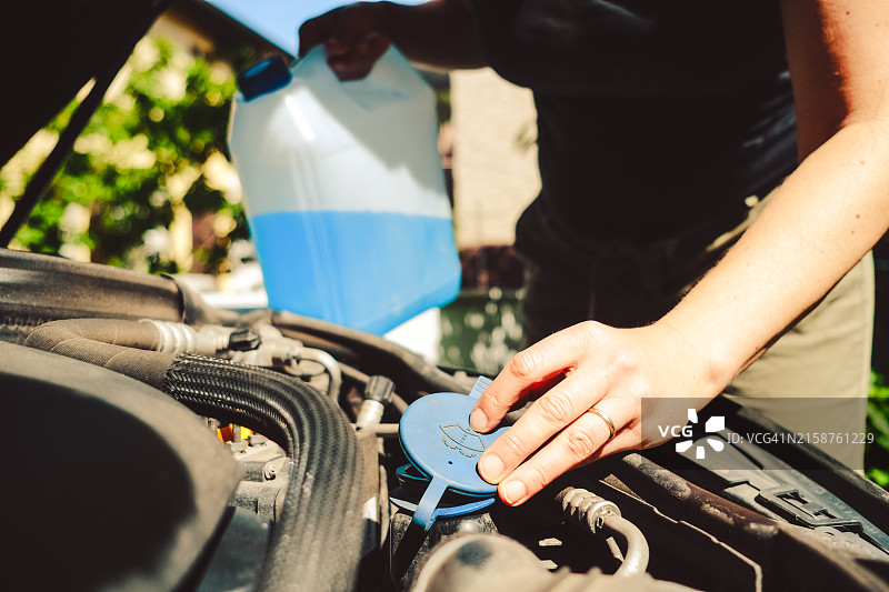 女人在后院更换汽车挡风玻璃清洗液图片素材