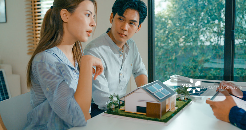 年轻的亚洲夫妇与房地产经纪人讨论投资太阳能住宅的财务和环境效益图片素材