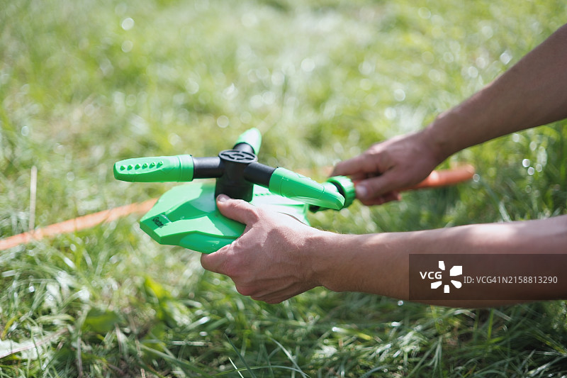 男子在草地上洒水图片素材