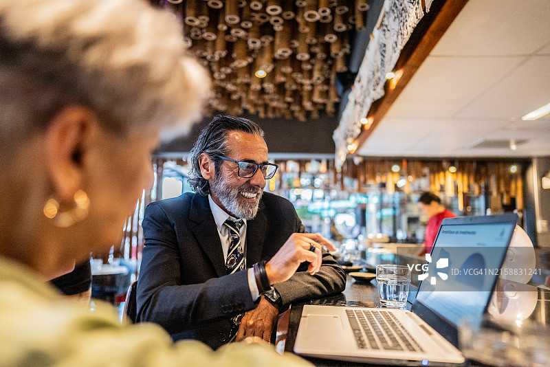 商人在日式餐厅与同事使用笔记本电脑图片素材