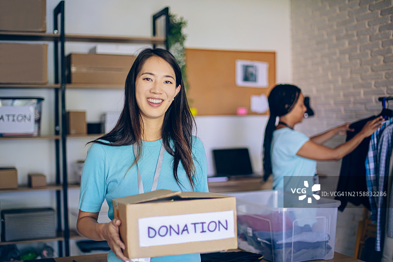 手持捐款箱的年轻亚洲女志愿者肖像图片素材