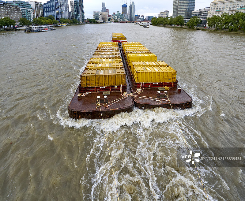 一艘拖船在伦敦东南部泰晤士河上拖着垃圾集装箱图片素材