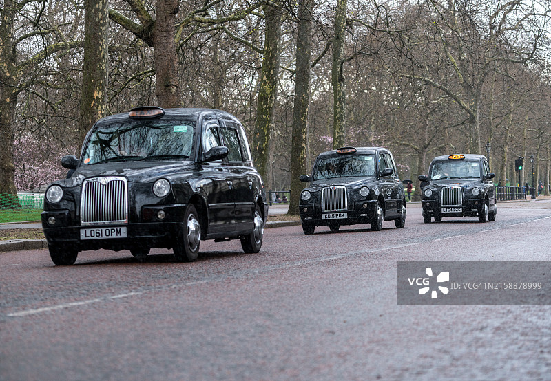 典型的传统英式出租车在伦敦林荫路附近雨中行驶图片素材
