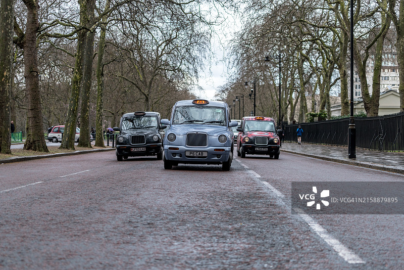 典型的传统英式出租车在伦敦林荫路附近雨中行驶图片素材