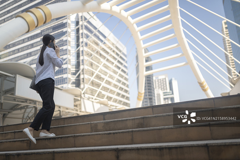 一个人穿着白衬衫和黑裤子走在现代建筑的城市区域的楼梯上图片素材