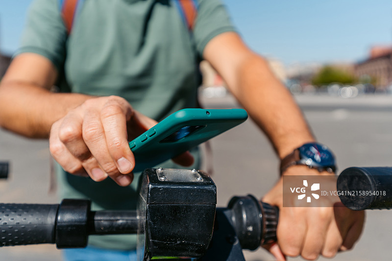 在亚美尼亚埃里温使用智能手机租用电动滑板车的中年男人图片素材