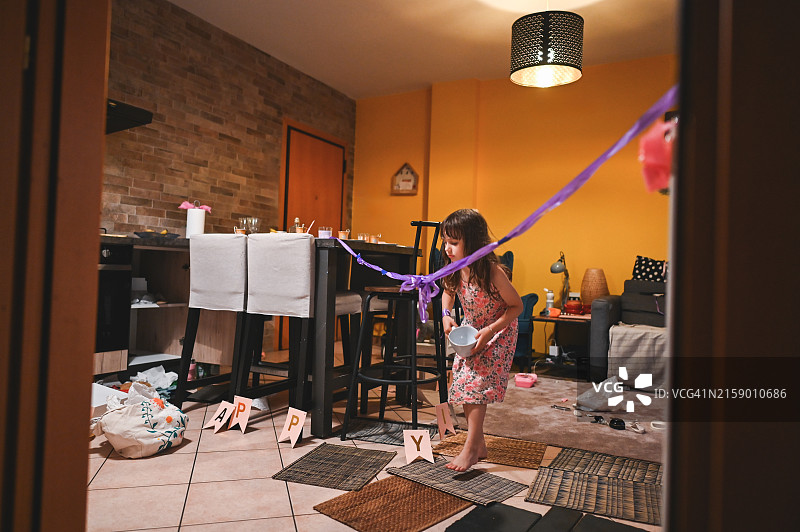 小女孩在凌乱的客厅里玩耍图片素材
