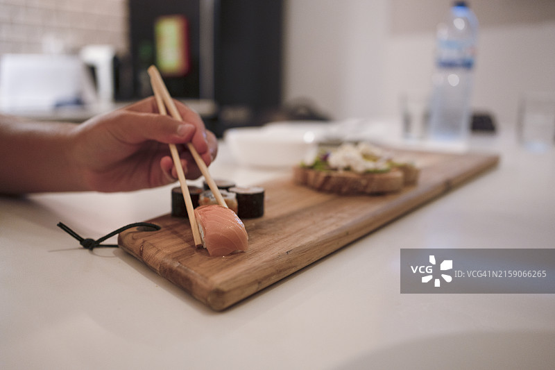 寿司拼盘特写：一位匿名人士用筷子夹起一块寿司图片素材