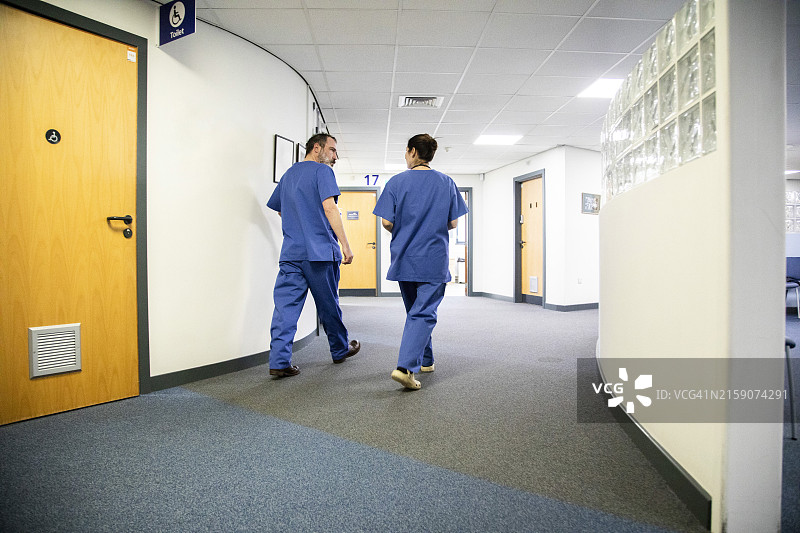 两名医护人员走在医院走廊里，英国医疗实践图片素材