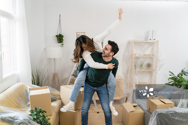情侣在新房里庆祝，周围是未拆封的箱子图片素材