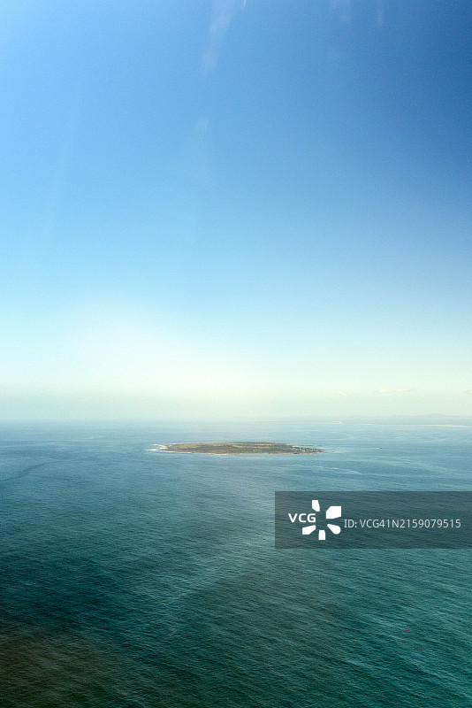 一览无余：蓝色海域中孤独小岛的鸟瞰图图片素材