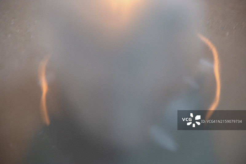 模糊的图像显示一个被朦胧光晕和柔和光线包围的人的轮廓图片素材