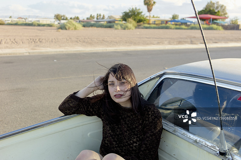 女子坐在经典汽车的开放式车窗中，背景是沙漠景观图片素材