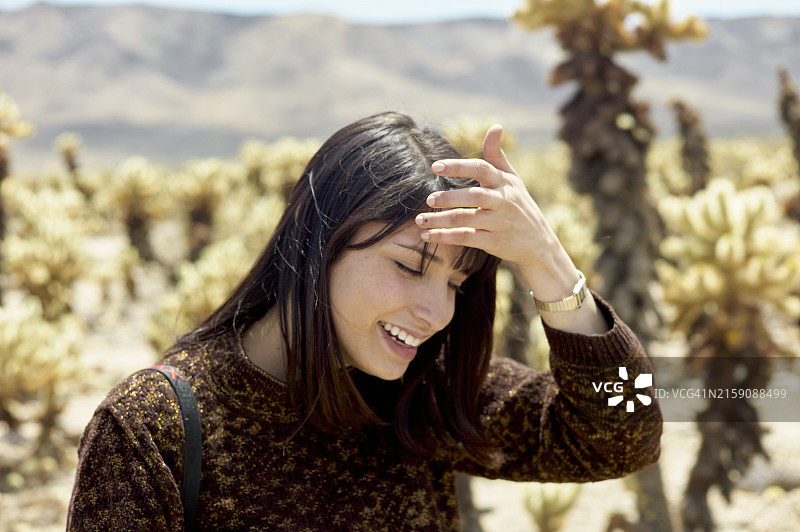 年轻女人户外微笑，仙人掌环绕。图片素材