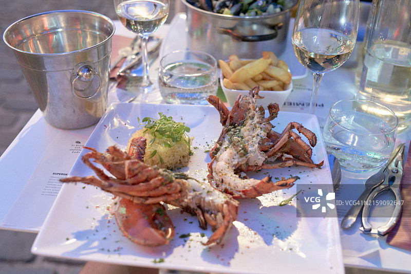 精致的龙虾美食，搭配白葡萄酒、水杯和炸薯条图片素材