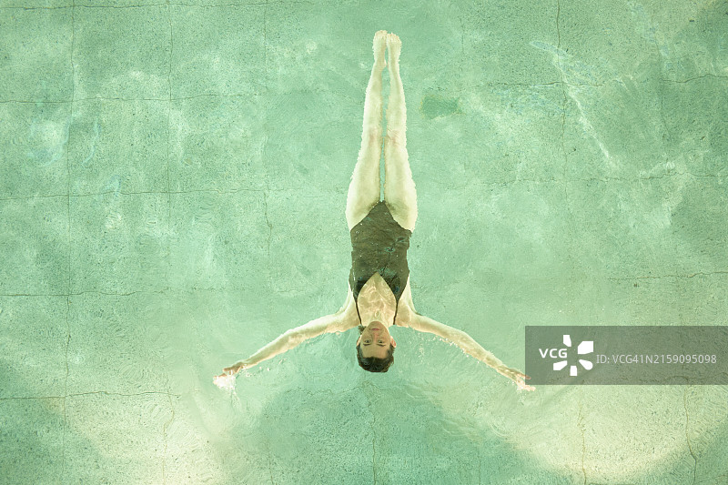 从上方拍摄的在碧绿泳池中游泳的人，画面宁静对称图片素材