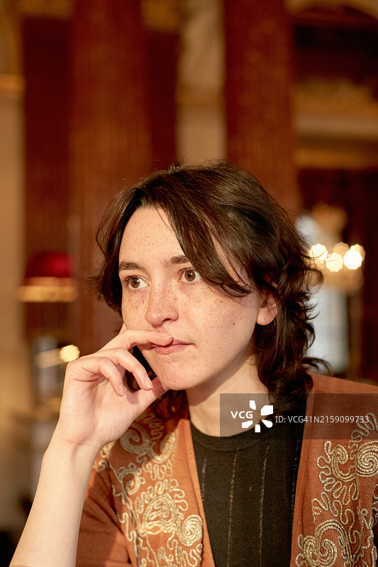 优雅的室内，手托下巴，若有所思的年轻女人图片素材
