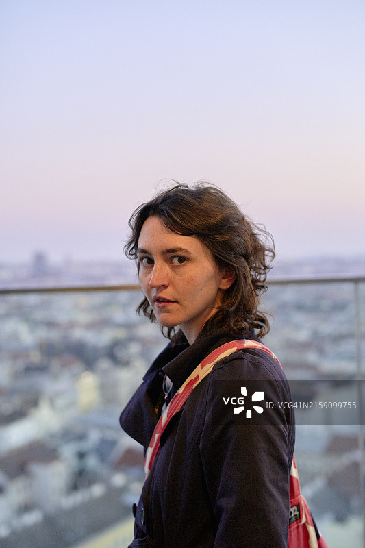 沉思的女人俯瞰黄昏时分的城市景观图片素材