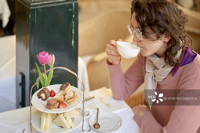 女子在优雅的户外咖啡馆享用茶点图片素材