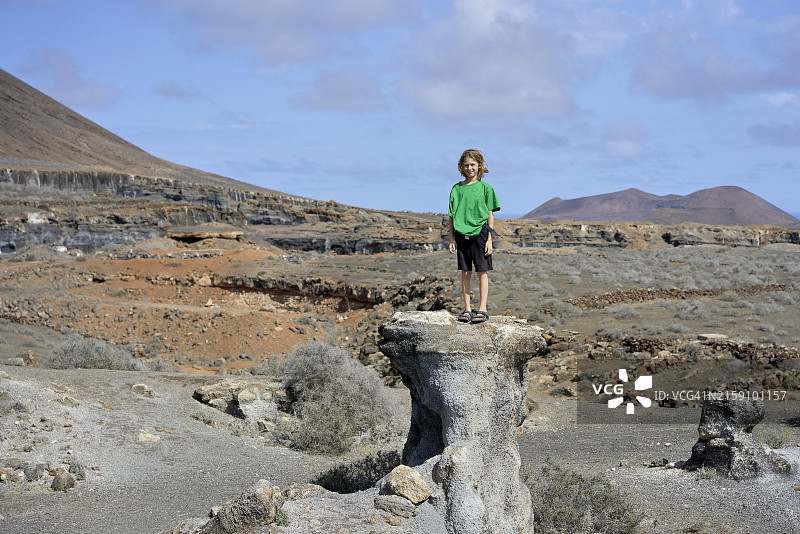 站在沙漠岩石上的男孩图片素材