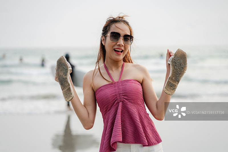 在夏季的沙滩上手持鞋子的女人图片素材