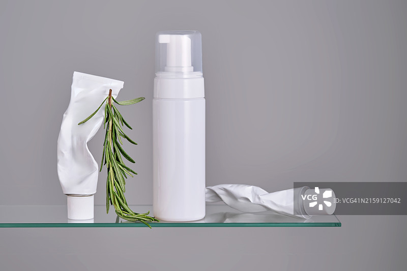 浴室玻璃架子上带有迷迭香的各种面部和身体护理产品图片素材