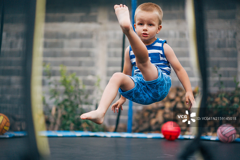 男孩在蹦床上跳跃图片素材