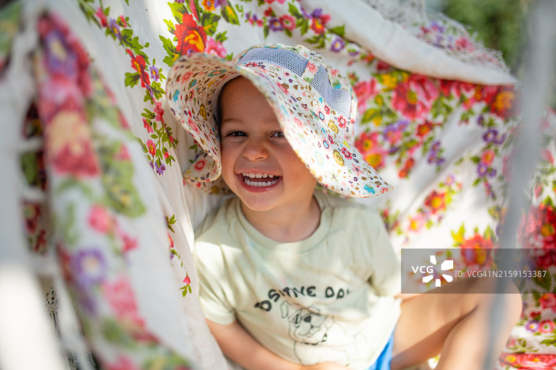 快乐的小男孩坐在吊床椅上微笑图片素材