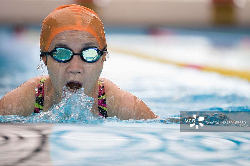 年长的亚洲女运动员在室内游泳池练习蛙泳图片素材