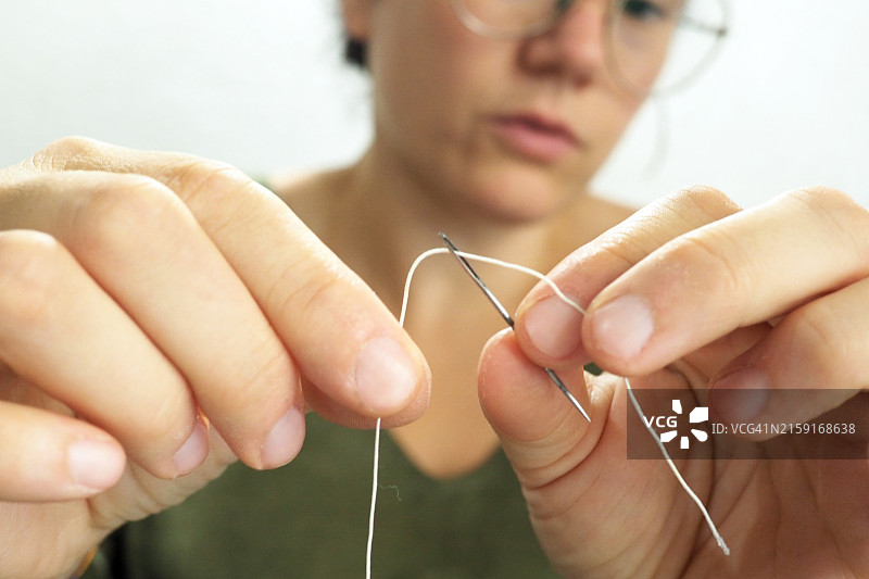 年轻女人的手穿针图片素材