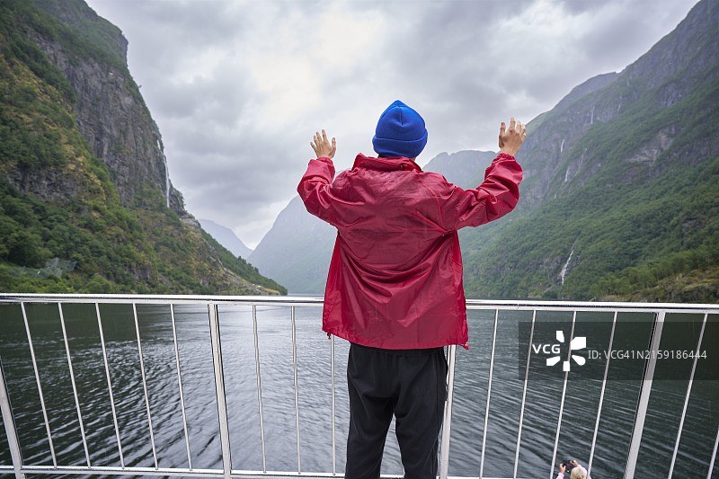 在挪威奥斯陆附近峡湾的船上，年轻的白人少年举起双臂图片素材