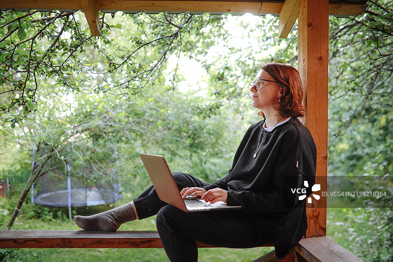 戴眼镜穿黑色西装的中年妇女在门廊工作图片素材