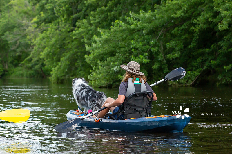 女孩和她的狗在河上划皮划艇图片素材