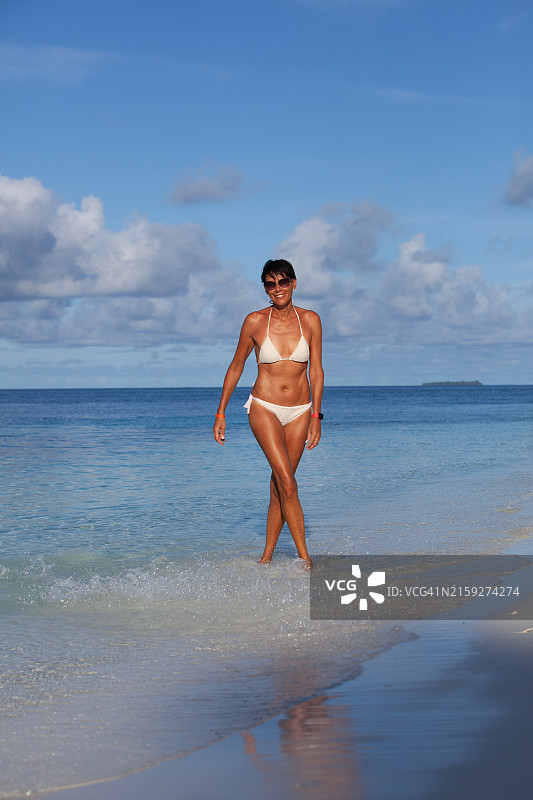 女人走在热带海滩的岸边图片素材