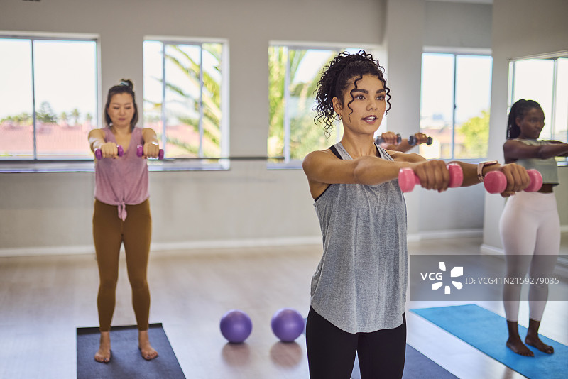 年轻女教练带领学生在工作室举哑铃图片素材