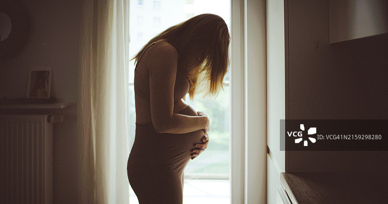 经历分娩阵痛的孕妇轮廓。她感到疼痛并触摸腹部图片素材