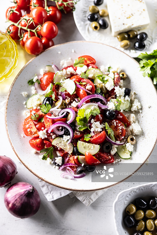 地中海沙拉配新鲜蔬菜、西红柿、菲达奶酪、黄瓜、西班牙洋葱和橄榄顶视图。健康食品概念图片素材