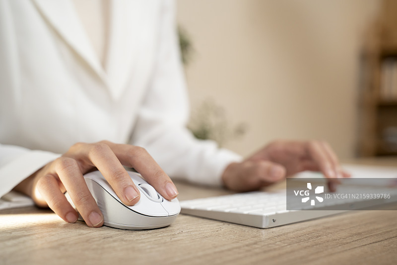 商务女人手，电脑鼠标和键盘在办公桌上打字，进行在线互联网搜索和数字营销，特写图片素材
