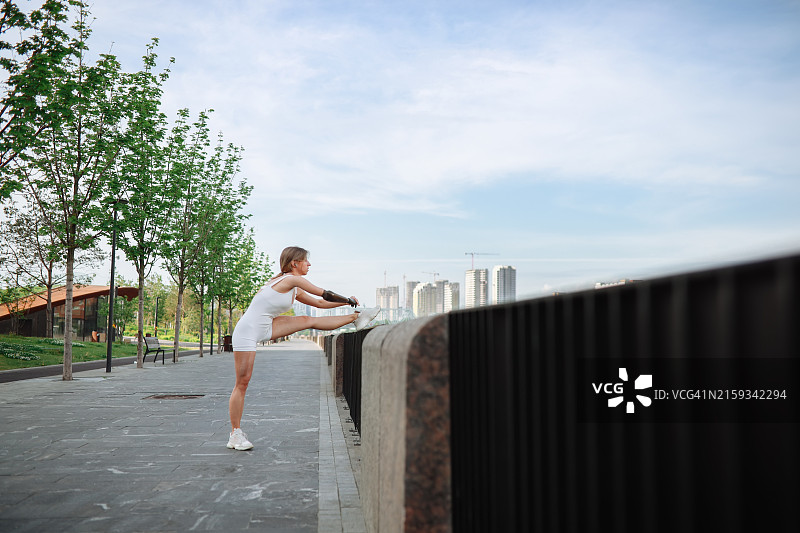 城市滨水区延伸：戴着假肢手臂的苗条女人穿着运动服准备跑步图片素材