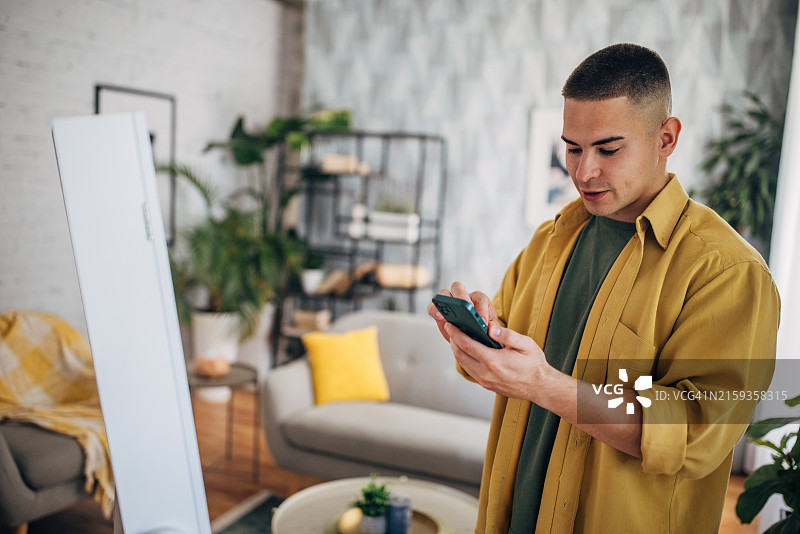专注的男人在家用智能手机发短信图片素材