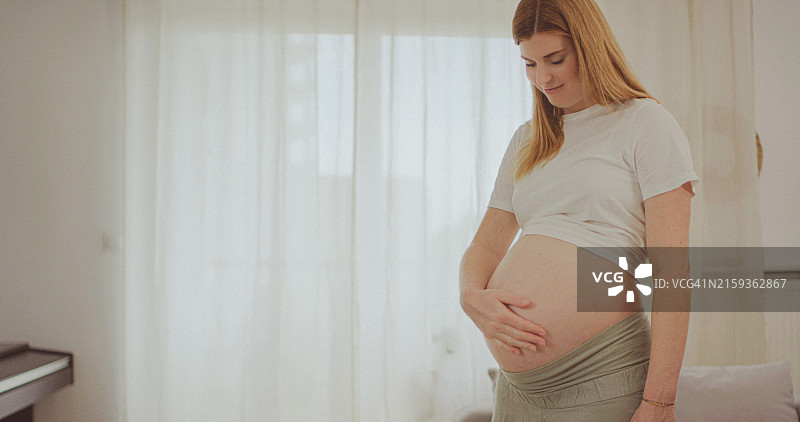 孕妇在家中抚摸腹部图片素材