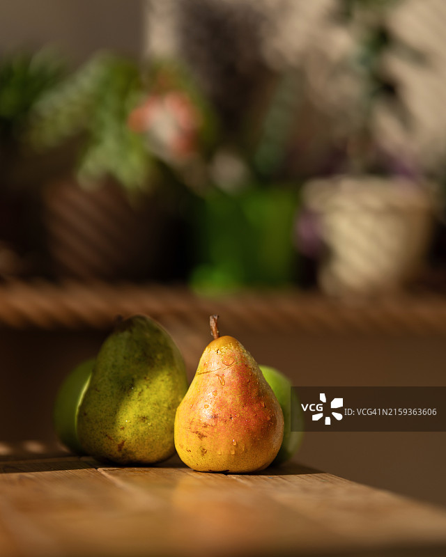 木桌上的新鲜梨子，带水滴的成熟水果，梨子和苹果，健康食品，木桌，侧视图，植物虚化背景图片素材