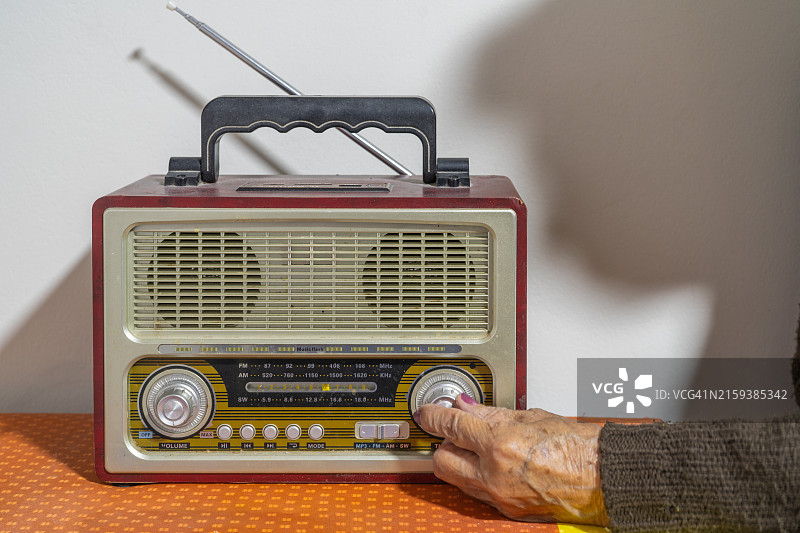 一位老妇人褶皱的手打开一台古董收音机图片素材