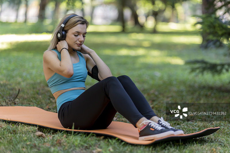 在公园里做仰卧起坐的年轻漂亮女人图片素材